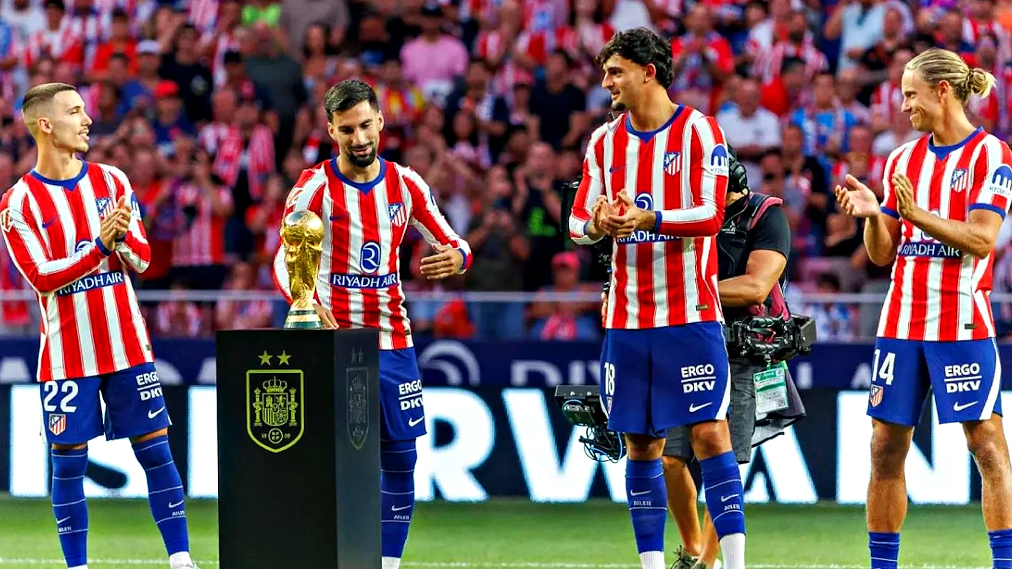 Jugadores del Atlético de Madrid junto a la Copa del Mundo sobre una peana negra