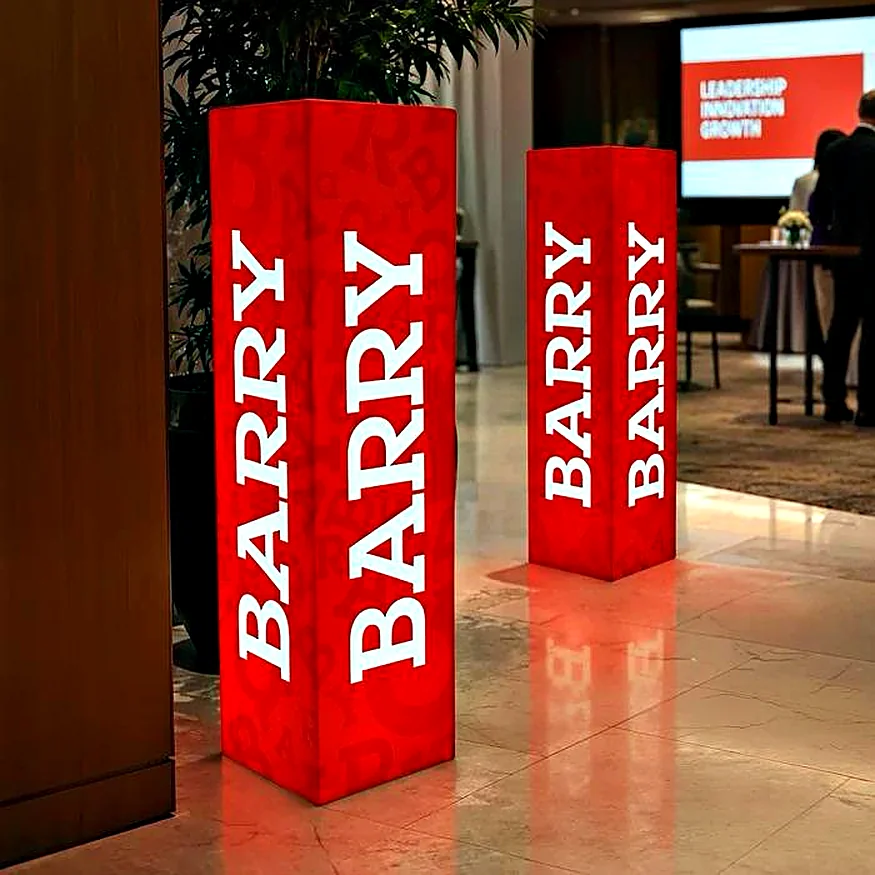 Tótems luminosos rojos con la marca Barry en un evento corporativo
